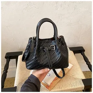 Nahaufnahme einer eleganten schwarzen gewebten Eimerhandtasche mit Griff und Gürteldetail.