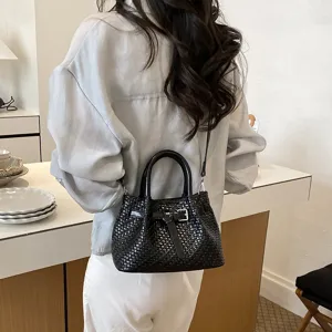 Detailansicht der stilvollen schwarzen geflochtenen Umhängetasche mit elegantem Riemen.