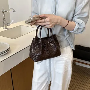 Nahaufnahme der dunkelbraunen geflochtenen Handtasche mit feiner Textur und tollem Schnallendetail.