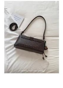 Detailed shot of dark brown woven shoulder bag on white cloth, minimalist retro daily accessory.