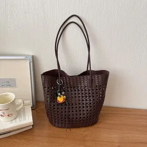 Nahaufnahme der dunkelbraunen geflochtenen Ledertasche mit feinem Lochmuster und Anhänger.