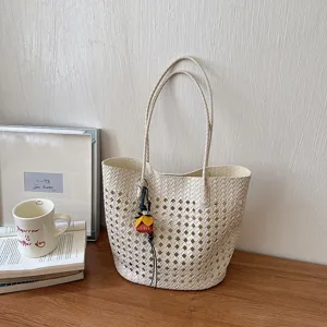 Detailaufnahme einer stilvollen beige geflochtenen Shopper Tasche auf Holztisch für den Alltag.