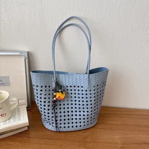 Blau geflochtene Cutout-Tragetasche, minimalistisches Design mit floralem Anhänger.