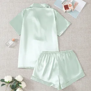 Detailed shot of mint green satin short sleeve pajama set with shorts flat lay scene.