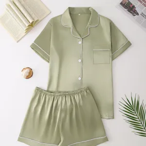 Close-up detail of green satin silk-like pajama set, short sleeve top and shorts flat lay.