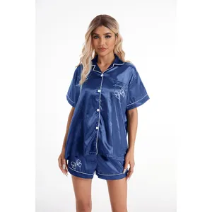 Conjunto de pijama de satén azul oscuro con mangas cortas, ribete blanco y bordado de lazo.