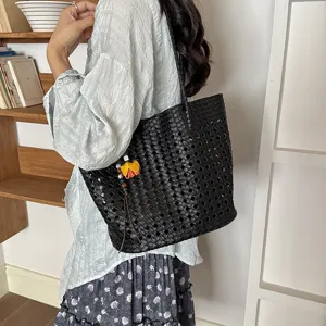 Nahaufnahme der eleganten schwarzen geflochtenen Handtasche mit Blumenanhänger im Regal.