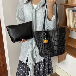 Schwarze geflochtene Cutout-Tragetasche mit passender Tasche und Blumenanhänger Detail.