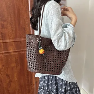 Detailansicht der braunen geflochtenen Ledertasche, elegante Aussparung mit Anhänger.