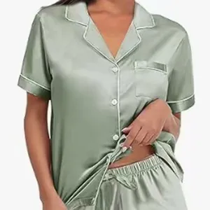 Detalle de pijama de satén, top de manga corta con botones, ribete blanco y pantalones cortos.