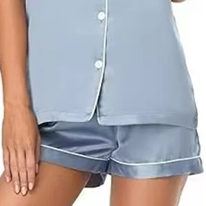 Primer plano detallado de un pijama de satén gris con manga corta y ribete blanco.