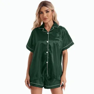 Detailed shot of women's short sleeve satin pajama set in dark green with white piping.