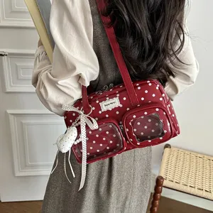 Détail de sac à bandoulière à pois rouges avec poches avant transparentes et joli pendentif.