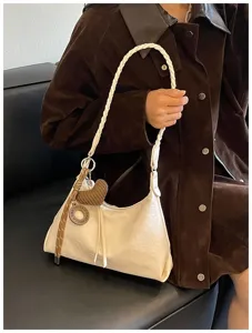 Vue détaillée du sac porté épaule blanc cassé avec une bandoulière tressée et un charm cœur.