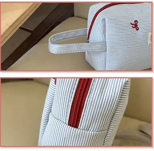 Blau-weiße gestreifte Kosmetiktasche Detail mit rotem Reißverschluss und Schleifenstickerei.