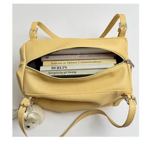 Detalle de la bolsa de hombro de cuero amarillo que muestra una gran capacidad.