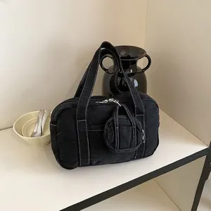 Detailed close-up of the black denim handbag featuring contrast white stitching and mini pouch.