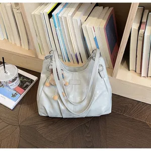 Detail view of a grey casual shoulder bag with furry pendant, minimalist design and large capacity.