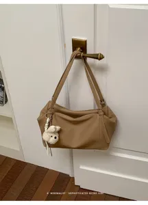 Vista detallada del bolso de hombro marrón colgado con un colgante de perrito adorable.