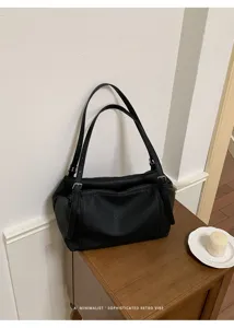 Vista detallada del bolso de hombro de cuero negro con textura premium y elegantes correas.