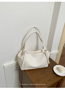 Vista detallada en primer plano del bolso de hombro de cuero blanco con hebillas.