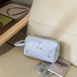 Detailaufnahme der blauen Kosmetiktasche mit Schleifenstickerei und praktischem Griff für Reisen.