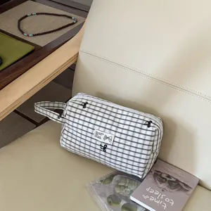 Detailansicht der karierten Kosmetiktasche mit Schleifenstickerei und praktischem Griff.
