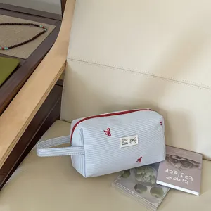 Blau-weiß gestreifter Kosmetikbeutel mit roter Schleifenstickerei, tragbare Make-up-Tasche.