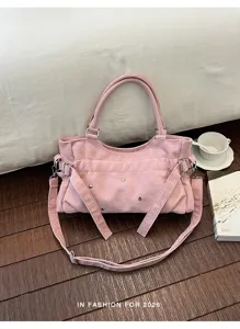 Detailed view of the pink suede shoulder bag featuring metal studs and stylish side buckles.
