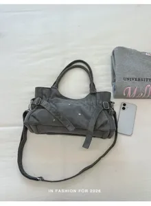 Detail shot of the gray suede underarm bag with chic metal rivets, showcasing the texture and strap.