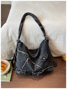 Close up of vintage dark grey denim shoulder bag with metal zippers and multi pocket details.