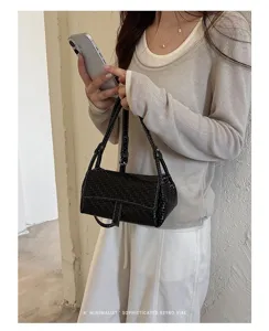 Minimalist woven shoulder bag detail shot, elegant black mini crossbody bag lifestyle presentation.