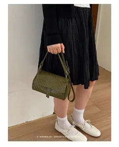 Detailed view of the dark green woven leather crossbody bag in a chic lifestyle scene.