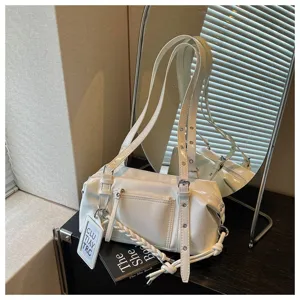 Close-up of white patent leather shoulder pillow bag detail with front pocket and hanging tag.