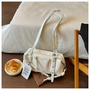 Detail view of white patent leather shoulder bag with double straps and front pocket design.