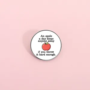 Close-up of a cute metal enamel pin with funny quote and apple graphic, detailed accessory.
