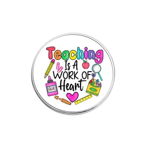 Round metal brooch badge featuring teacher appreciation design with colorful school supplies art.