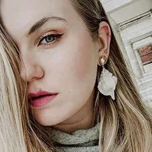 Close-up detail shot of the elegant drop earring worn by the model, highlighting texture.