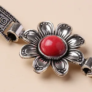 Close-up detail shot of vintage antique silver flower bracelet featuring red stone centerpiece.