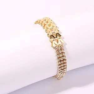 Dettaglio bracciale con strass dorati che mostra maglie a M intrecciate e cristalli scintillanti.