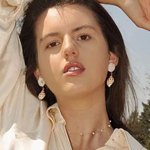 Close-up detail shot of elegant shell drop earrings paired with a delicate pearl choker necklace.