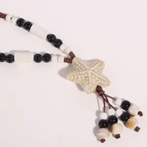 Close-up detail of ethnic style ceramic starfish pendant necklace with black and white beads.