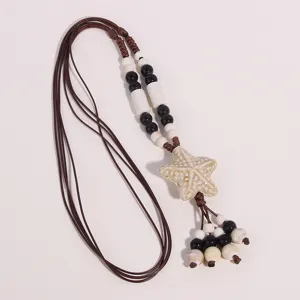 Detailed close-up of ethnic ceramic starfish necklace pendant featuring black and white beads.