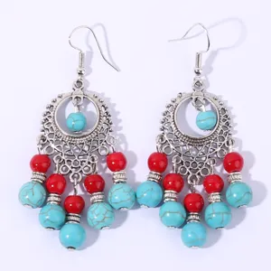 Close-up detail of vintage bohemian turquoise and red bead tassel drop earrings in silver.