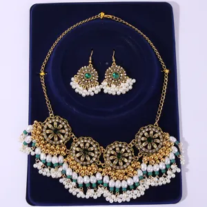 Detailed shot of bohemian vintage gold tone necklace and earrings set with green and pearls.
