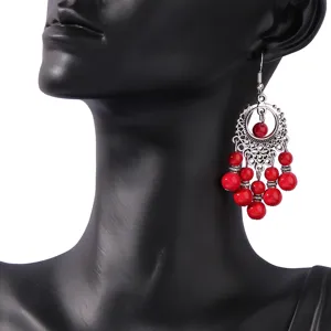 Close-up detail of retro red beaded silver dangle earrings, ethnic bohemian style jewelry.