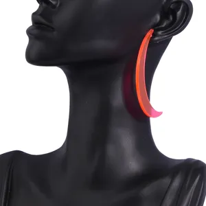 Close-up detail shot of neon orange acrylic crescent earrings, trendy party jewelry for women.