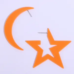 Close-up detail of orange acrylic star and moon asymmetrical earrings for summer.