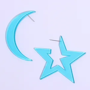 Close-up detail of bright blue acrylic star and moon asymmetric earrings for summer.