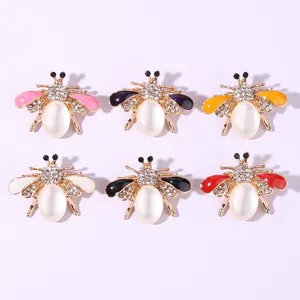 Close-up of vibrant rhinestone bee brooches featuring colorful enamel wings and pearl bodies.